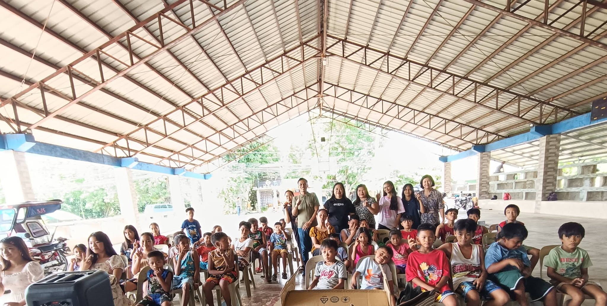 Children seated at a covered court during a ministry program