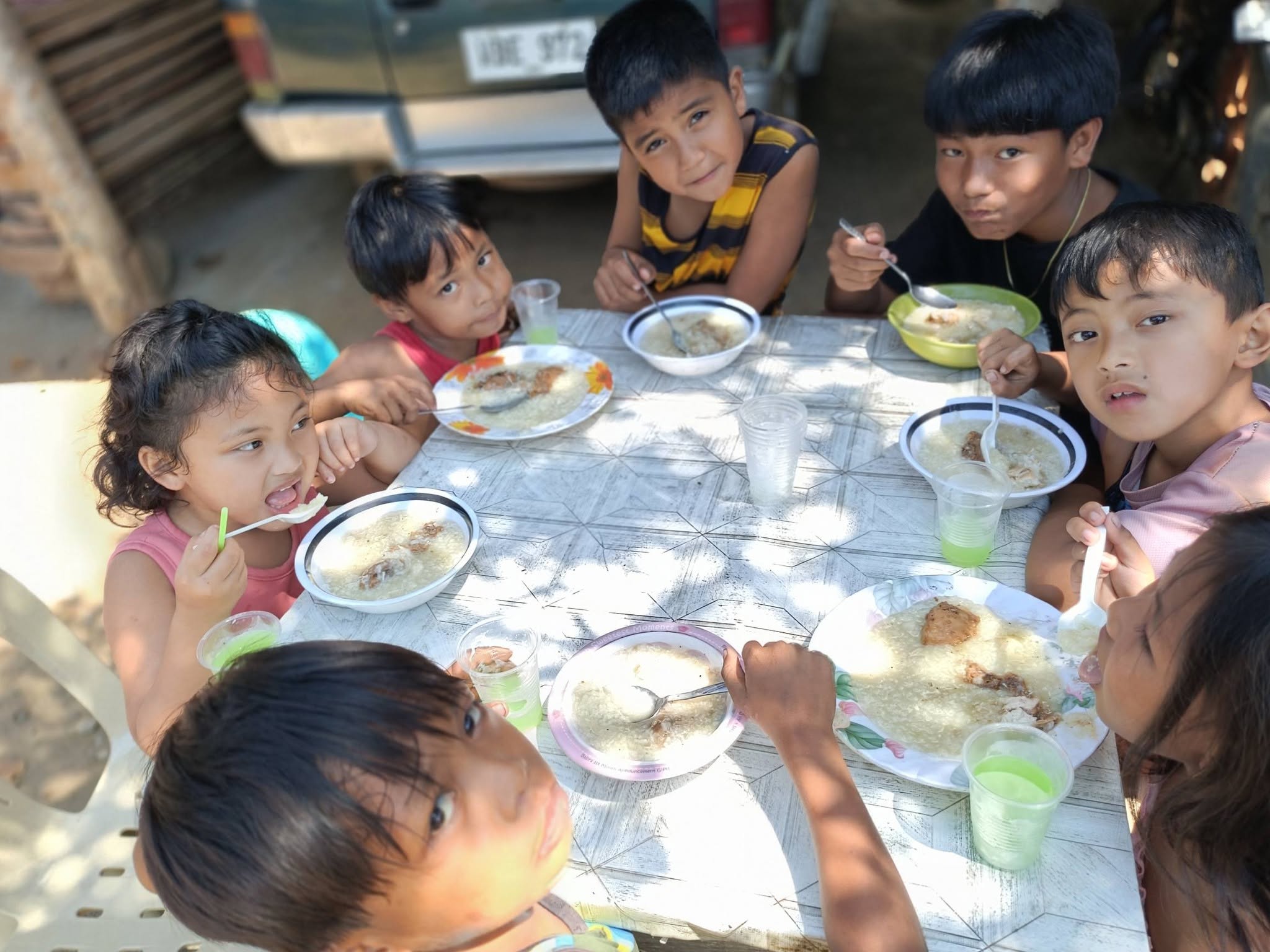 Children sharing a warm meal of rice porridge around a table
