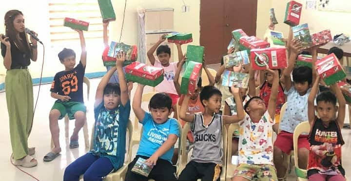 Children joyfully lifting gift boxes above their heads