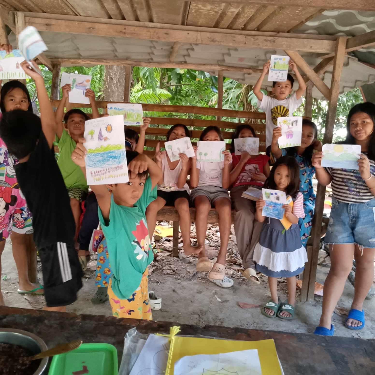 Children proudly holding up drawings they made during a lesson