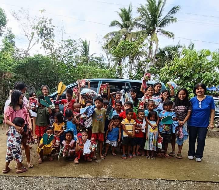 Children and volunteers gathered around the ministry van during a village outreach, holding gifts
