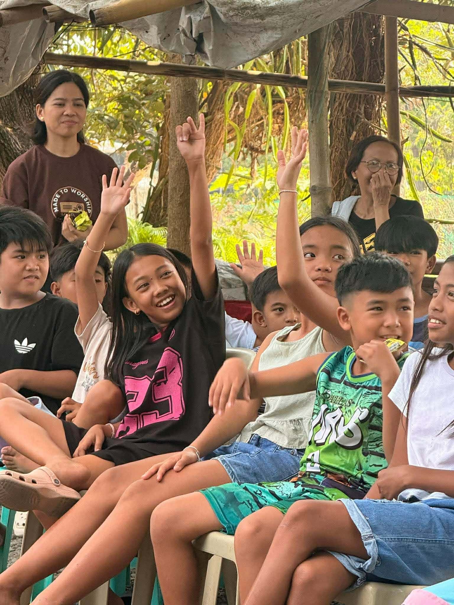 Smiling children eagerly raising their hands during a lesson